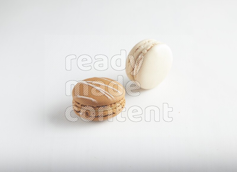 45º Shot of of two assorted Brown Irish Cream, and White Caramel fleur de sel macarons on white background