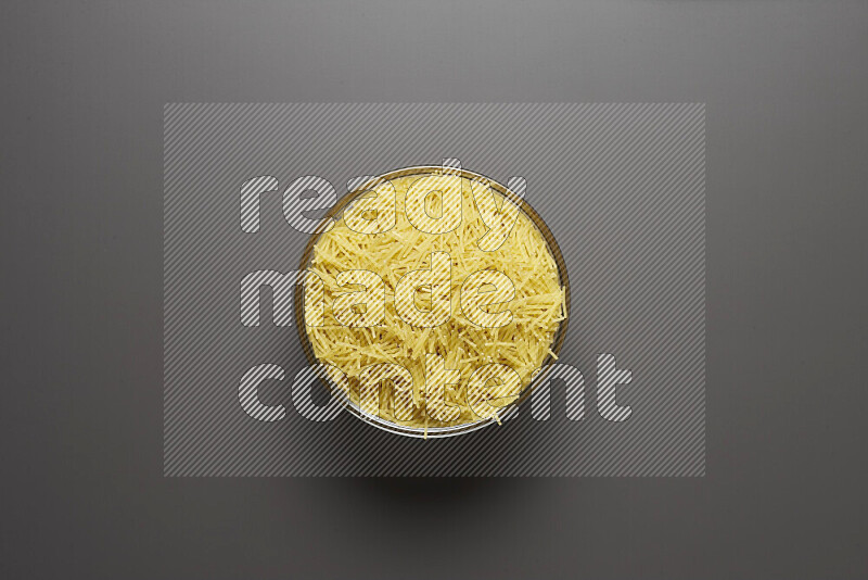 Vermicelli pasta in a glass bowl on grey background