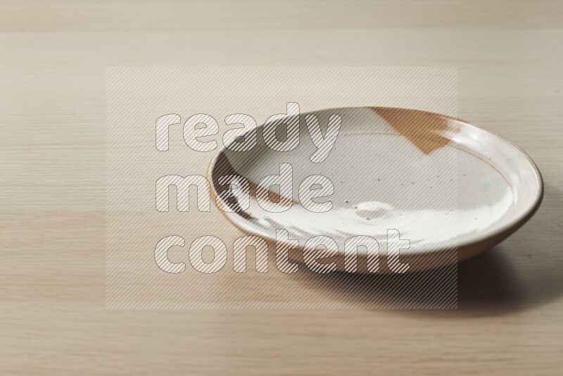 A multicolored pottery plate on light wooden background