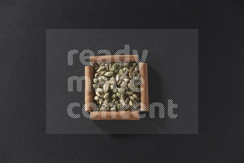 A single square of cinnamon sticks full of Cardamom on black flooring