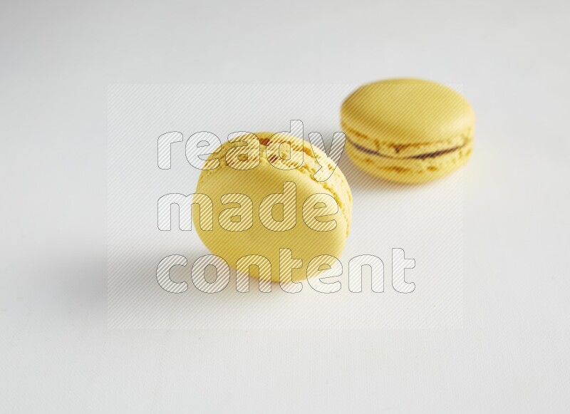 45º Shot of two Yellow Lemon macarons on white background