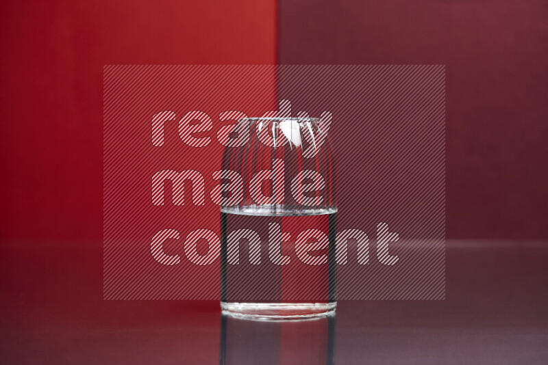 The image features a clear glassware filled with water, set against red and dark red background