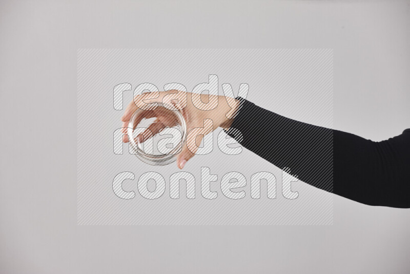 A woman in black abaya holding different glassware in different positions