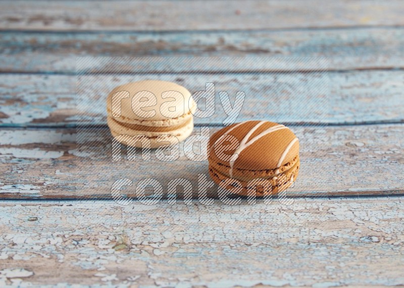 45º Shot of of two assorted Brown Irish Cream, and White Caramel fleur de sel macarons on light blue background