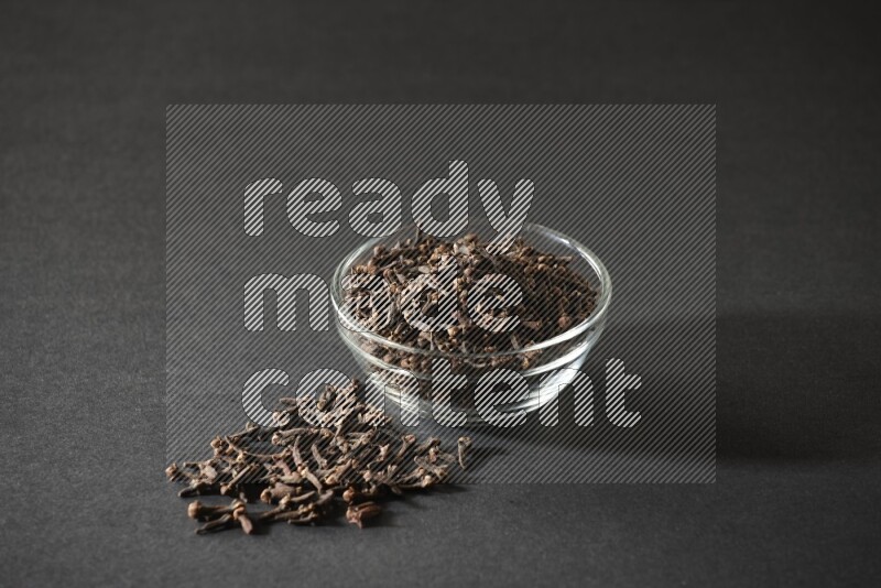 A glass bowl full of cloves on a black flooring