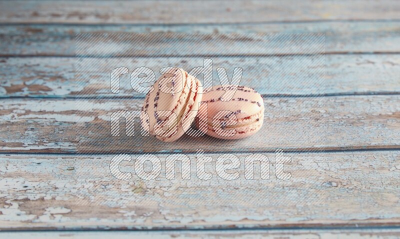 45º Shot of two pink orange blossom macarons on light blue wooden background