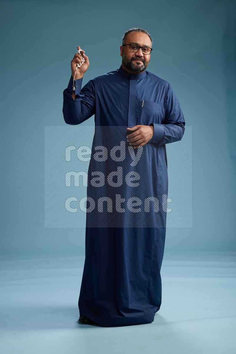 Saudi Man without shimag Standing Interacting with the camera on blue background
