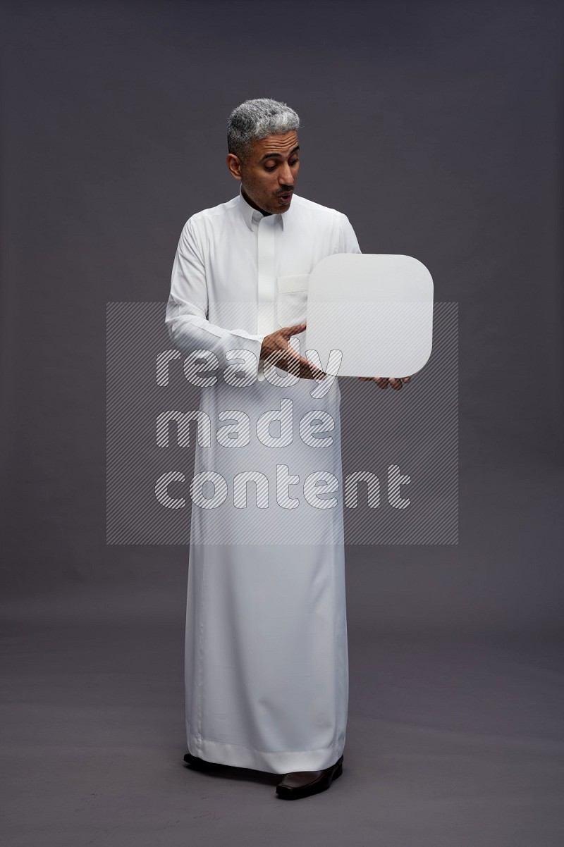 Saudi man wearing thob standing holding social media sign on gray background