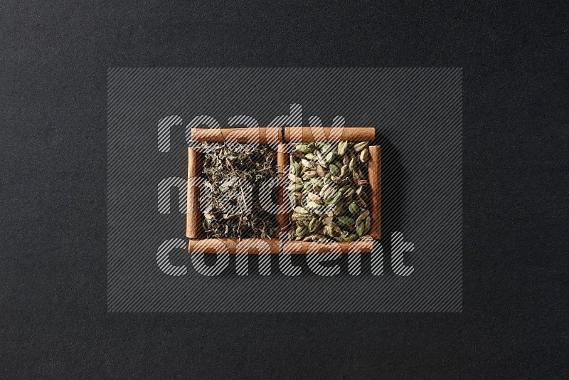 2 squares of cinnamon sticks full of cardamom and dried basil on black flooring