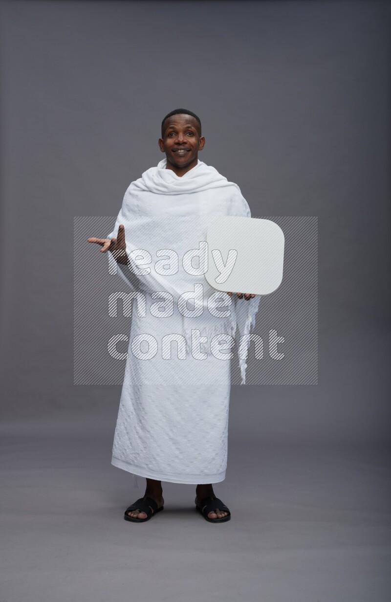 A man wearing Ehram Standing holding social media sign on gray background