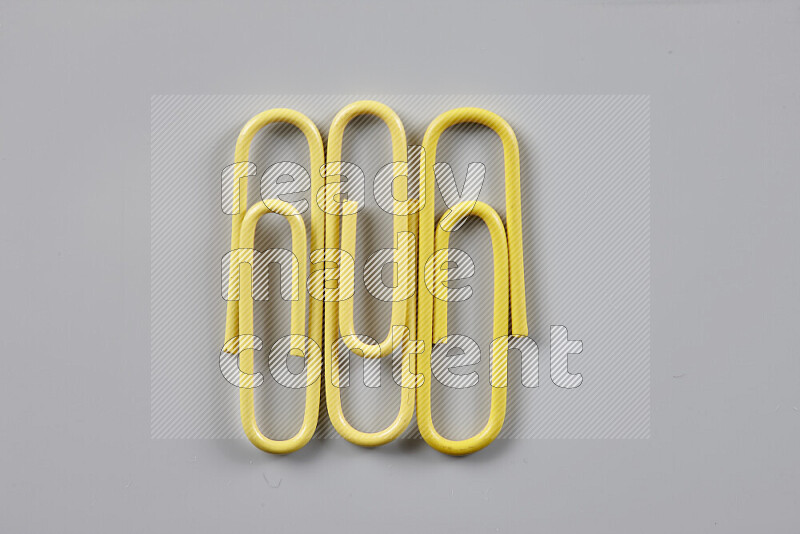 Yellow paper clips isolated on a grey background