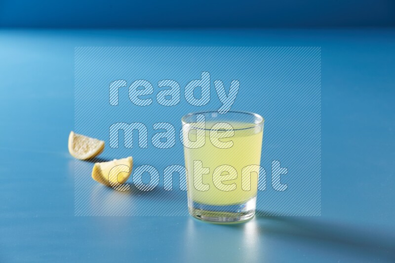 glass of lemon juice on blue background