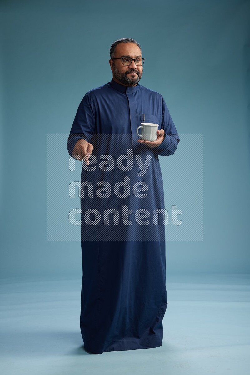 Saudi Man without shimag Standing drinking coffee on blue background
