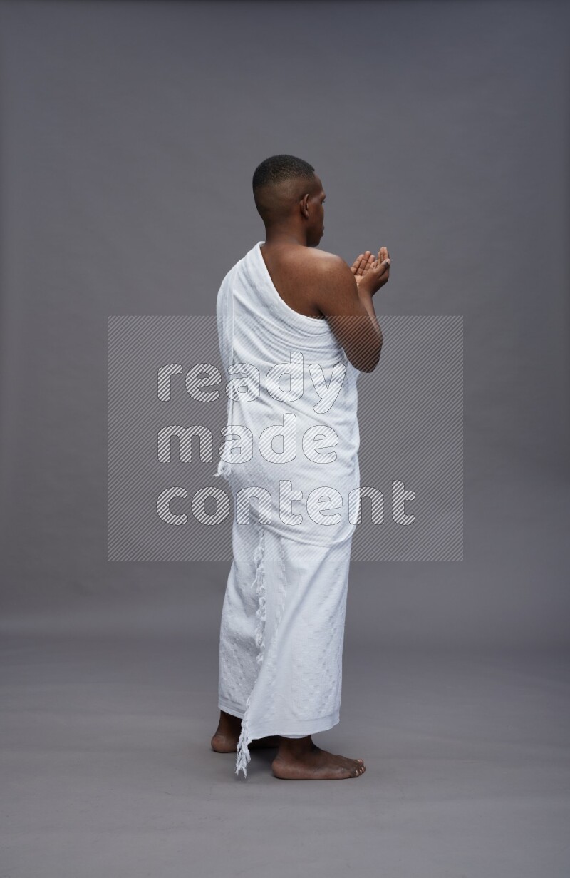 A man wearing Ehram Standing dua'a on gray background