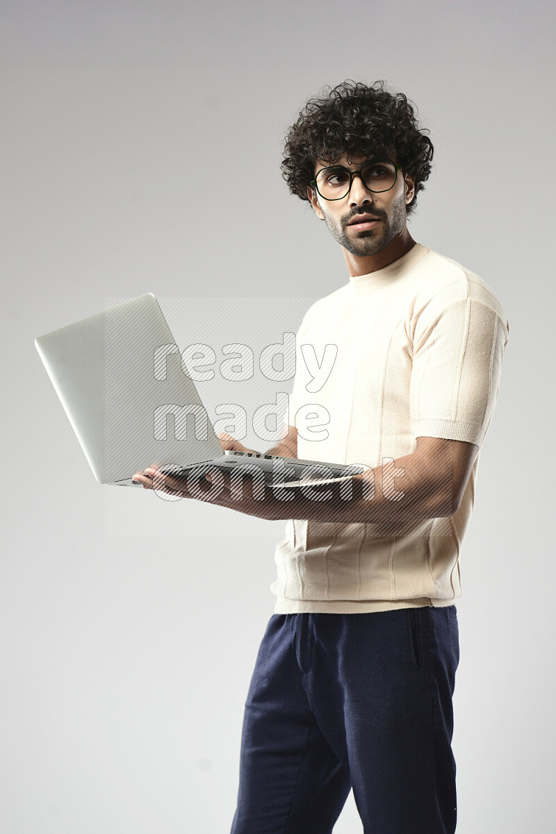 A man wearing casual standing and working on a laptop on white background