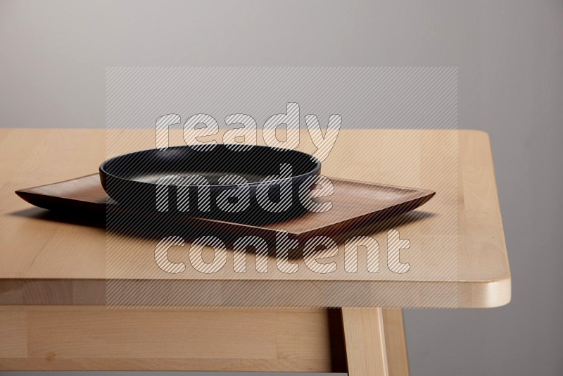black plate on a rectangular wooden tray on the edge of wooden table