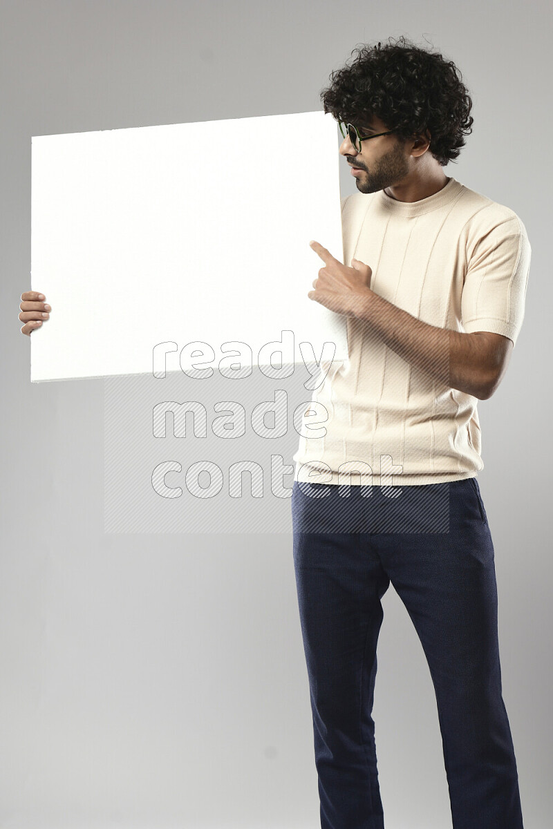 A man wearing casual standing and holding a white board on white background