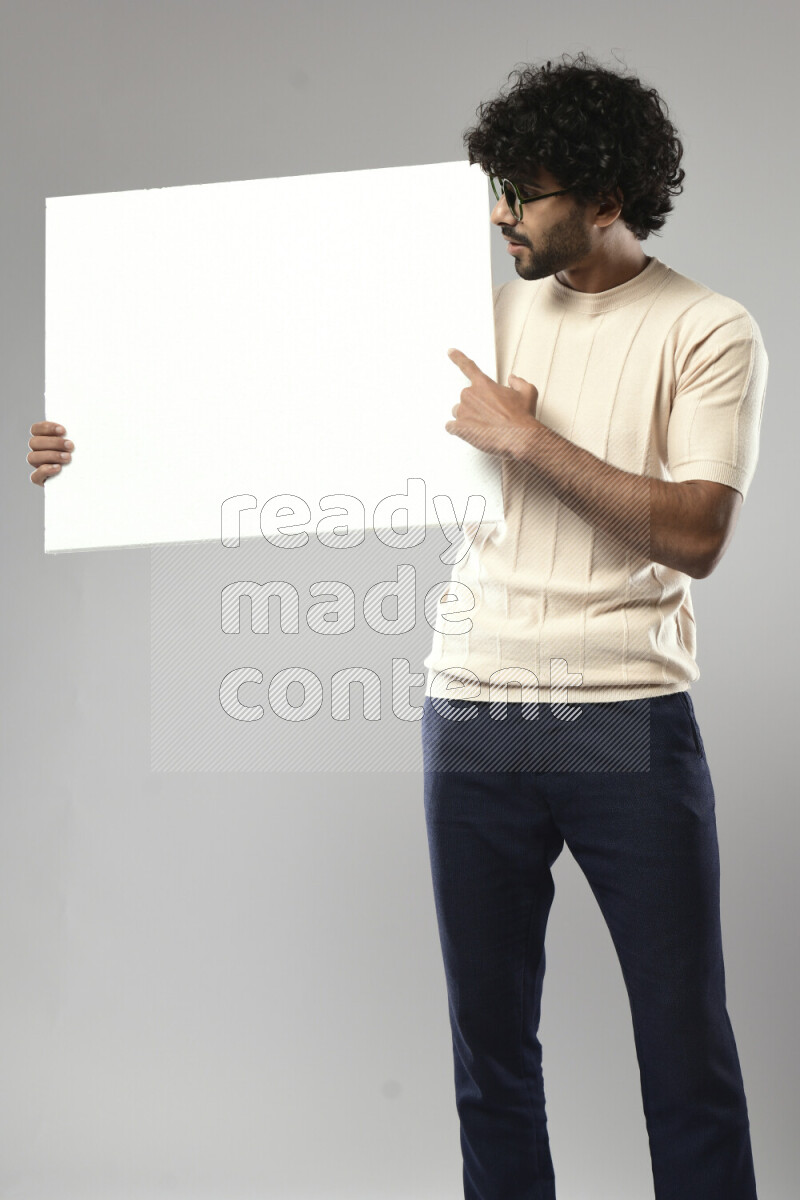 A man wearing casual standing and holding a white board on white background