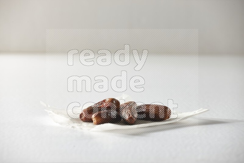 Dried dates on a crumpled piece of paper on a white background in different angles