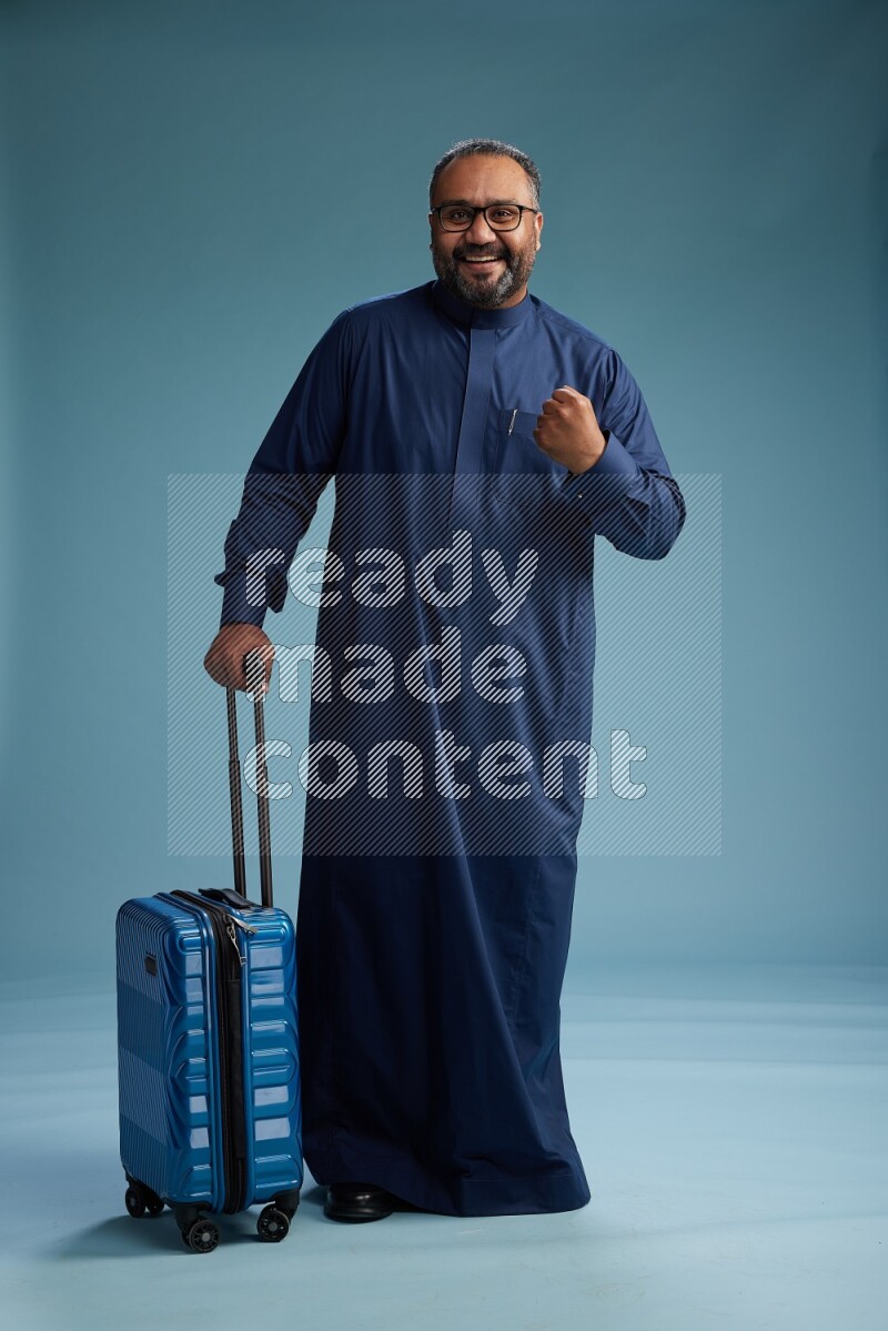 Saudi Man without shimag Standing pulling travel bag on blue background