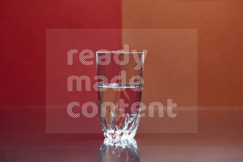 The image features a clear glassware filled with water, set against red and dark orange background