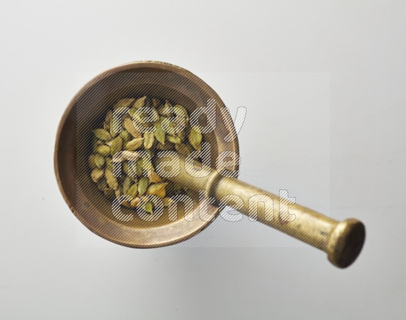 Top-view shot of Cardamon in herbs crusher on white background