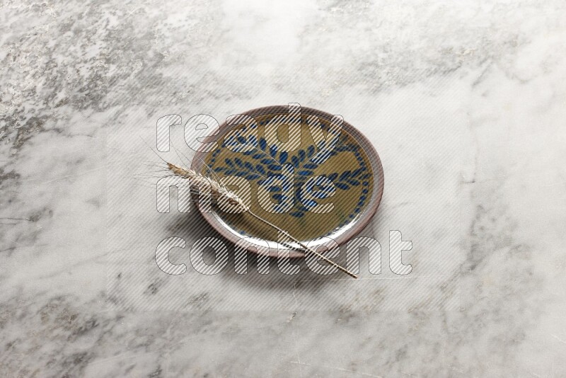 Wheat stalks on decorative pottery plate on grey marble background