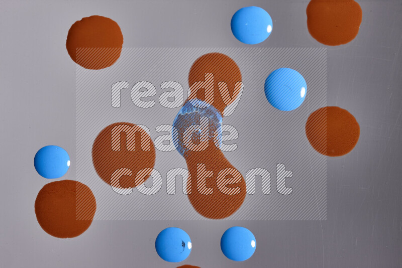 Close-ups of abstract orange and blue paint droplets on the surface