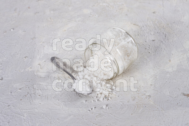 A glass jar full of coarse sea salt crystals on white background