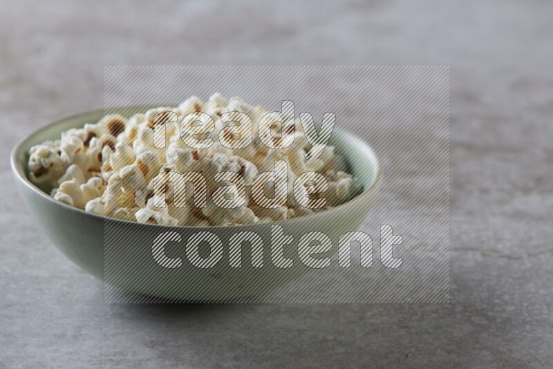 popcorn in green bowl on a grey textured countertop