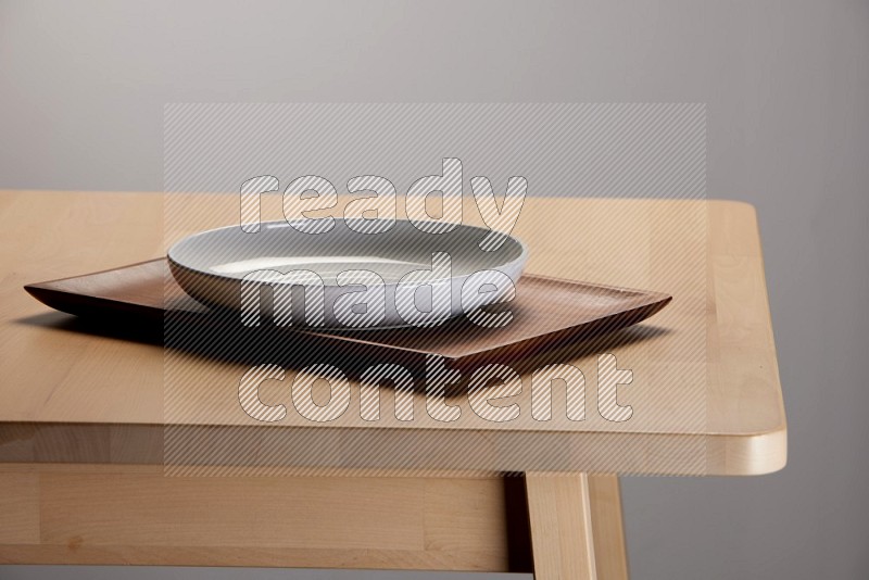 white plate on a rectangular wooden tray on the edge of wooden table