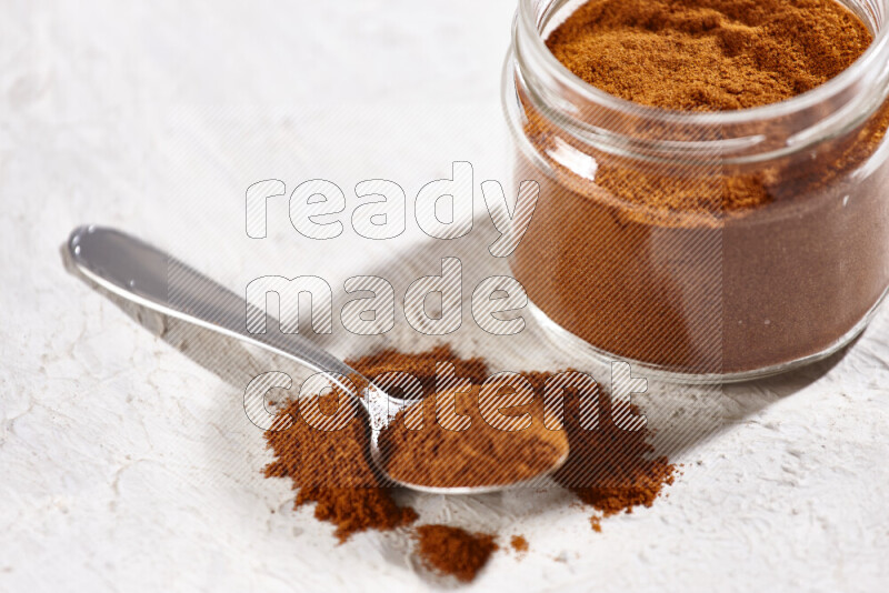 A glass jar full of ground paprika powder on white background