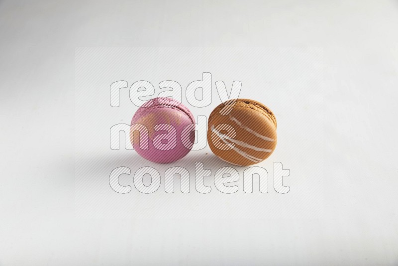 45º Shot of of two assorted Brown Irish Cream, and Purple Strawberry macarons on white background