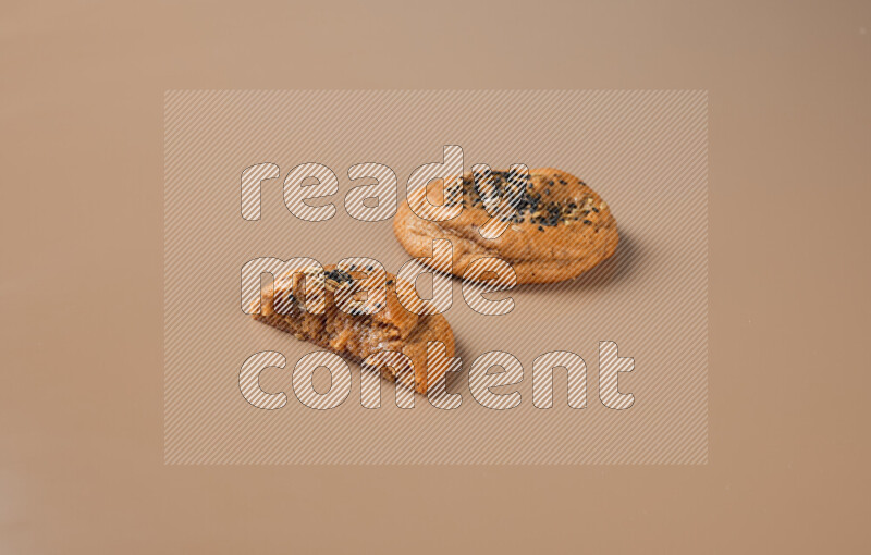a Hasawi cookie field of date and herbs with another one cut in half on a brown background