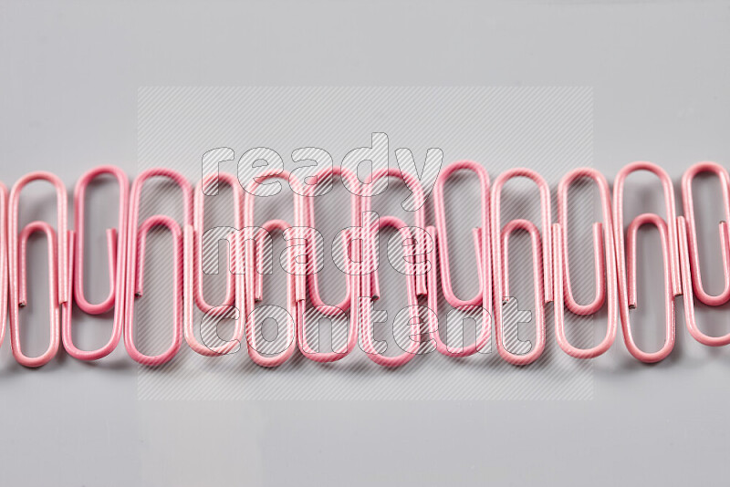 Pink paperclips isolated on a grey background