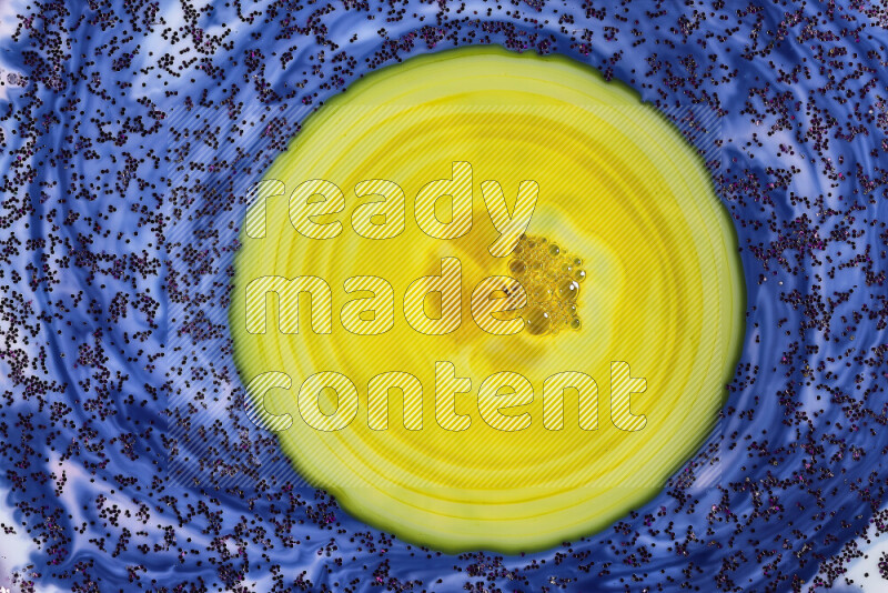 A close-up of sparkling purple glitter scattered on swirling blue and yellow background