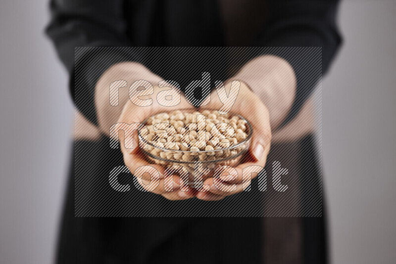 Woman in abaya holding different kinds of legumes in different positions