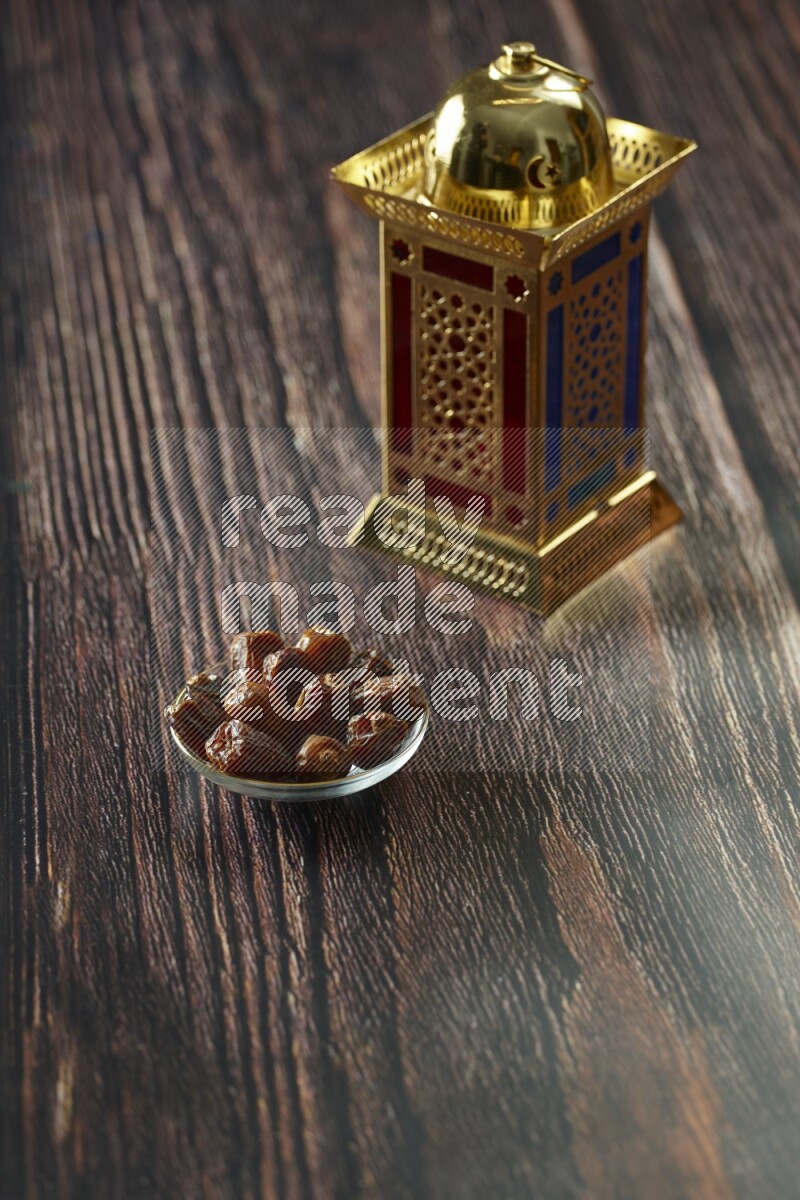 A golden lantern with different drinks, dates, nuts, prayer beads and quran on brown wooden background