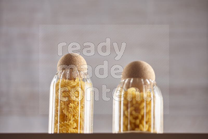 Raw pasta in glass jars on beige background