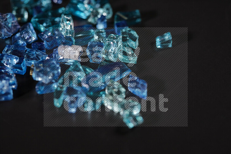 Transparent blue fragments of glass scattered on a black background