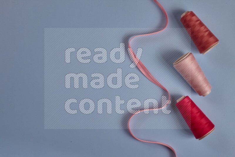 مجموعة من أدوات الخياطة والتفصيل زهرية اللون على خلفية زرقاء