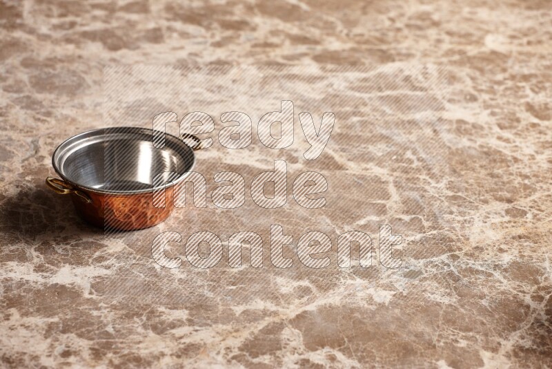 A small copper pot on beige marble background