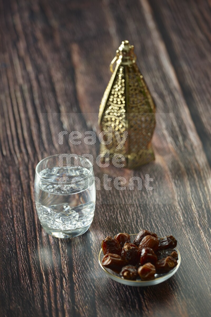 A golden lantern with different drinks, dates, nuts, prayer beads and quran on brown wooden background