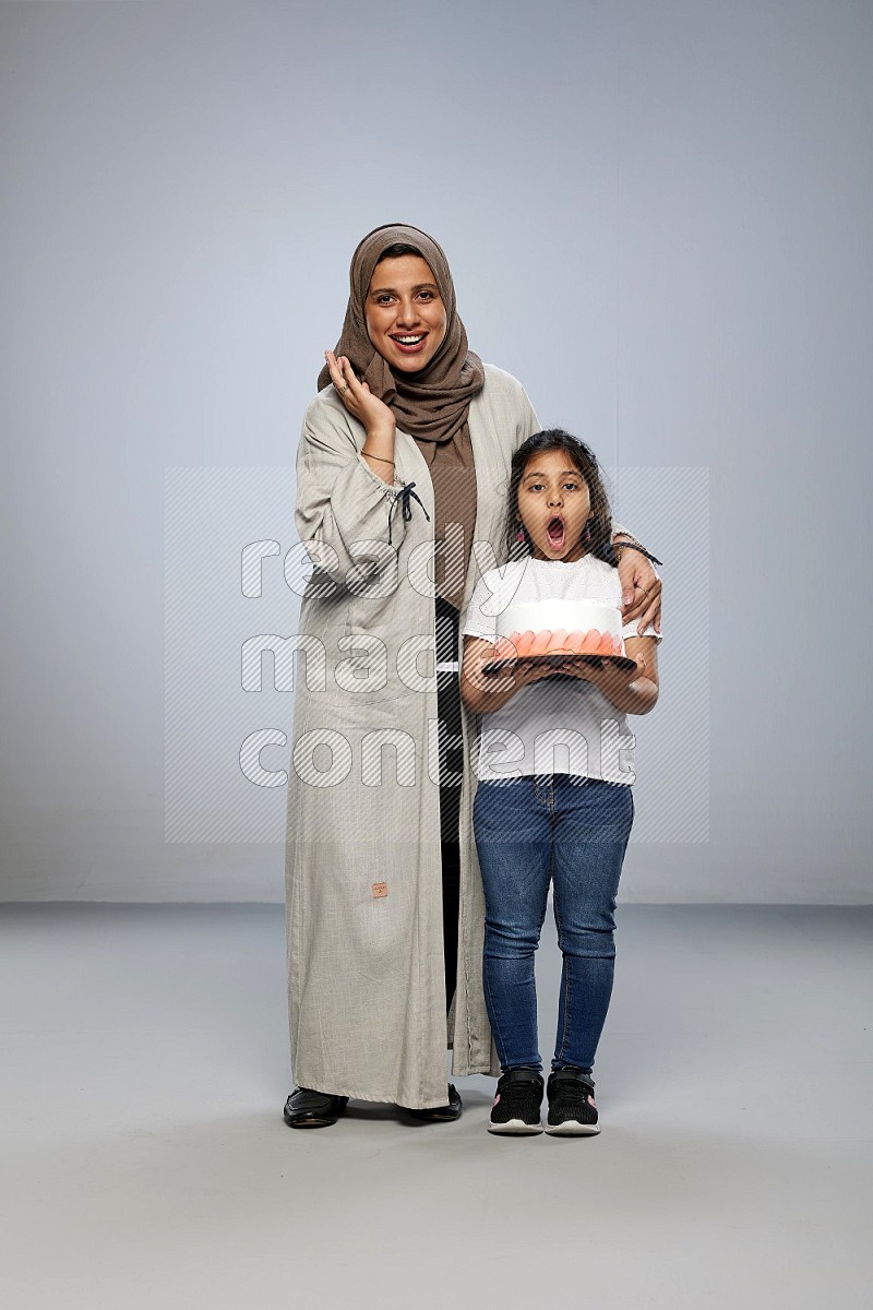 A girl giving a cake to her mother on gray background