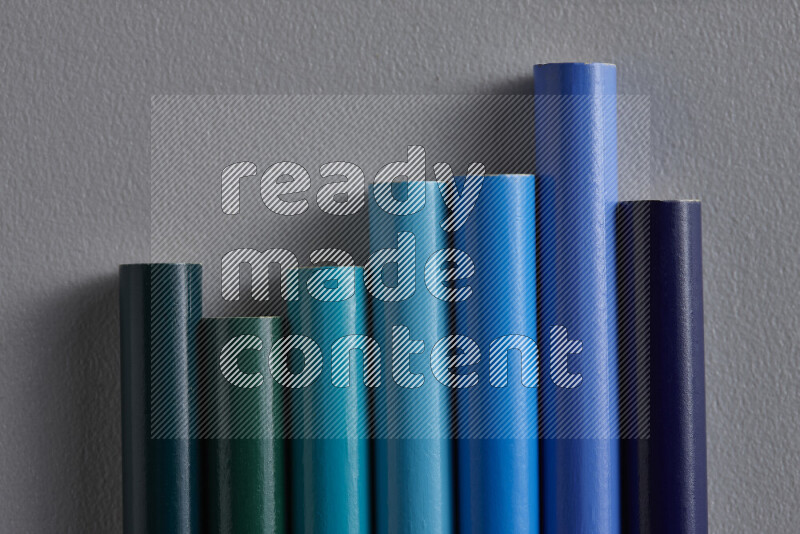 A collection of colored pencils arranged showcasing a gradient of blue hues on grey background