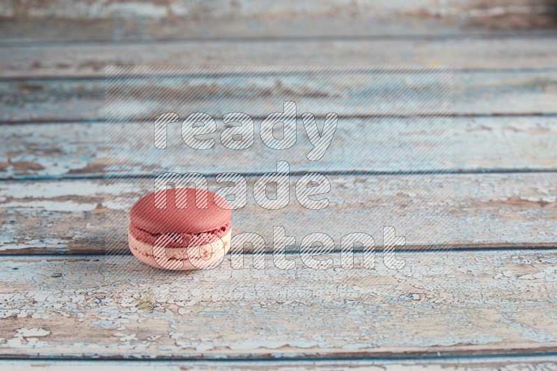 45º Shot of Pink Litchi Raspberry macaron on light blue wooden background