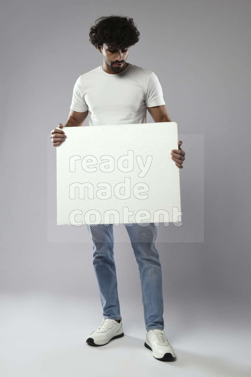A man wearing casual standing and holding a white board on white background