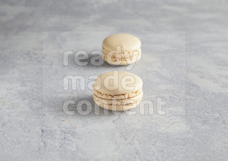 45º Shot of two white marbleCaramel fleur de sel macarons  on white  marble background