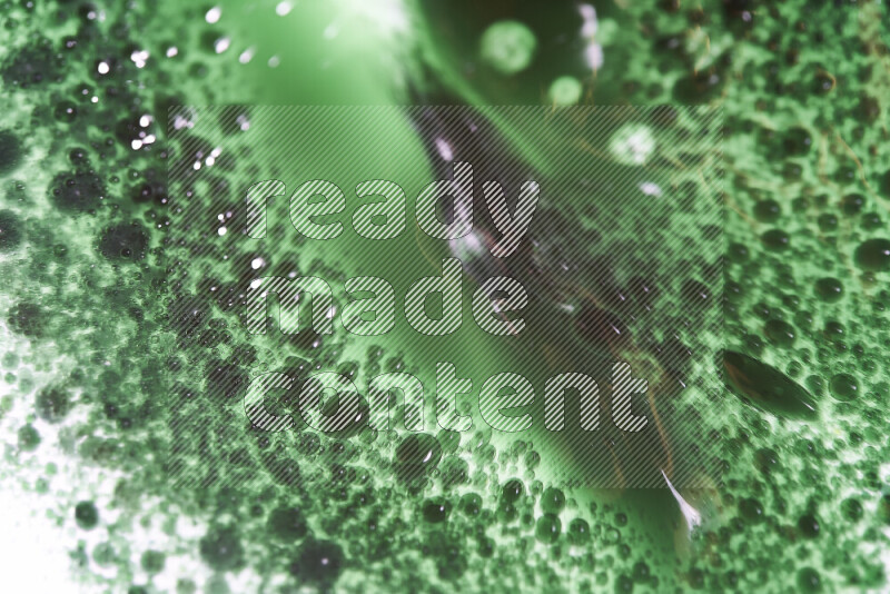 Close-ups of abstract green watercolor drops on oil Surface on white background