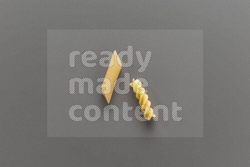 Penne pasta with other types of pasta on grey background